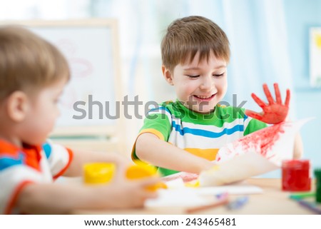 smiling kids playing and painting at home or kindergarten or playschool