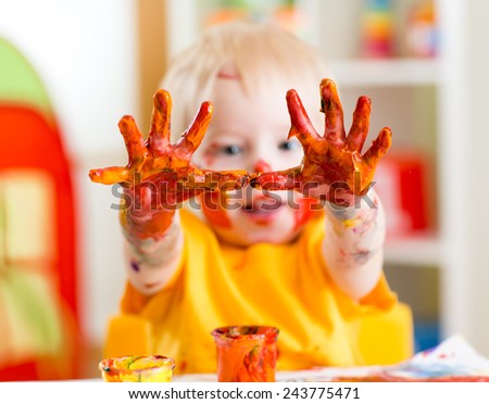 Happy child boy with painted hands at home