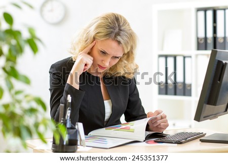 middle-aged businesswoman working in office and examining reports