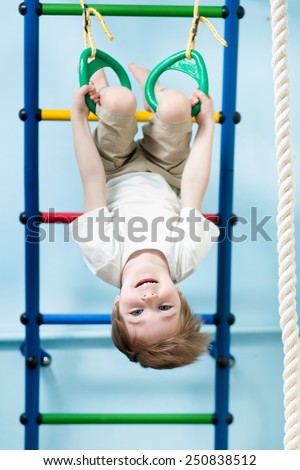 kid boy hanging on gymnastic rings at home