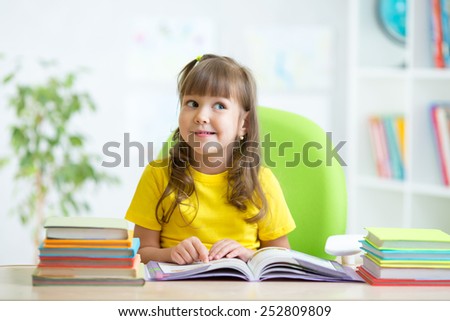 cute smiling child girl reading book at home