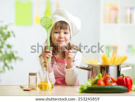 Kid girl cook makes healthy vegetables meal in the kitchen