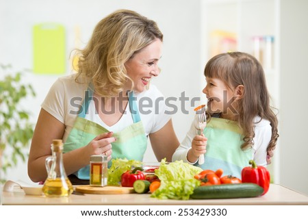 mother and kid daughter preparing healthy food and having fun
