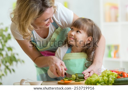 mother and kid girl cooking and cutting vegetables on kitchen