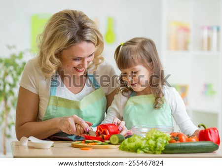 mother and her daughter preparing vegetables at kitchen