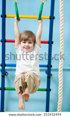 cute child boy hanging on gymnastic rings at home
