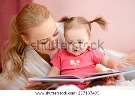 pretty mom reading a book to baby daughter at home