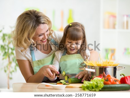 Cute mother teaches kid child cooking on kitchen