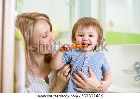 mother teaching son child teeth brushing in bathroom