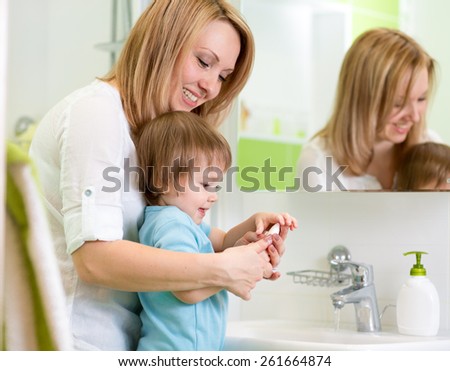 mother teaches son child hands washing with soap in bathroom