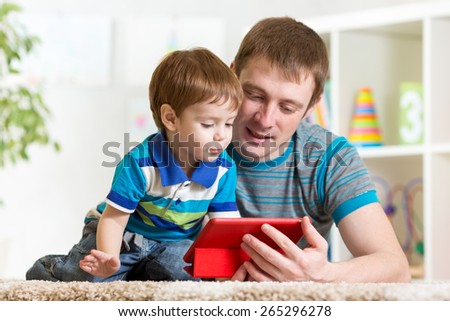 father and his child son play with tablet pc At home