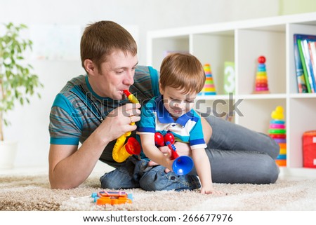 kid and his dad play musical toys at home