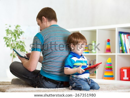 Loneliness of child boy and father playing with tablet at home