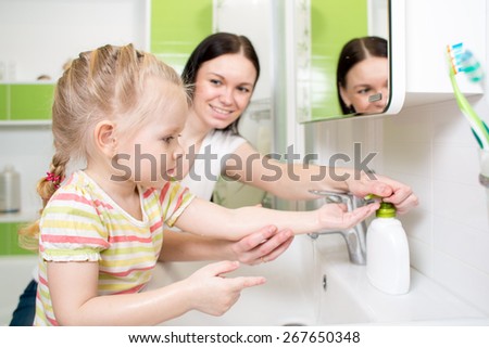 Happy kid with mom washing hands in the bathroom
