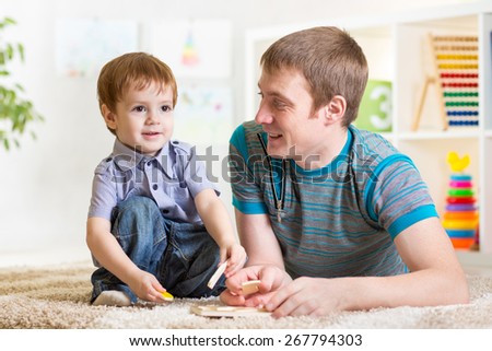 Child boy and father play with puzzle toy at home