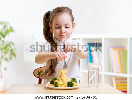 child girl eating healthy food at home or kindergarten