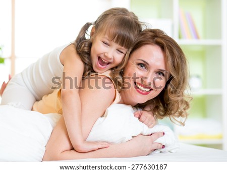 Happy mother and child girl having fun in bedroom