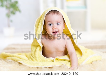 smiling baby with a towel after the shower on floor at home