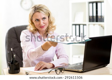 Middle-age business woman giving folder to co-worker