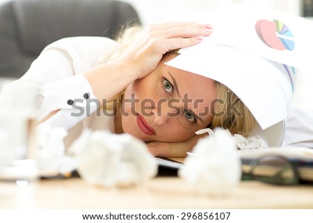 Tired female executive filling out documents while sitting at her desk