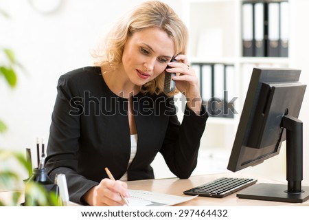 Middle-age businesswoman talking on the mobile phone in office. Portrait of smiling business woman.