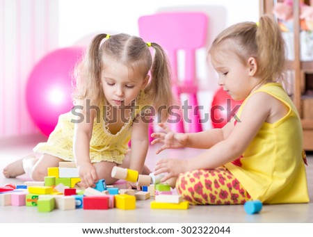 Children playing with wooden blocks laying on the floor in their room
