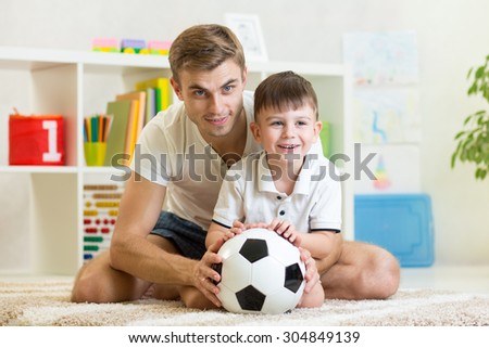 child boy with daddy play foot ball at home
