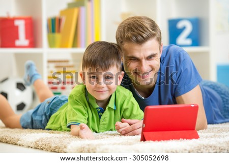 father and his child son play with tablet pc