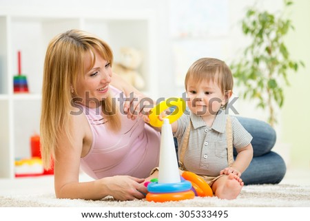 child boy with mom playing together in nursery at home