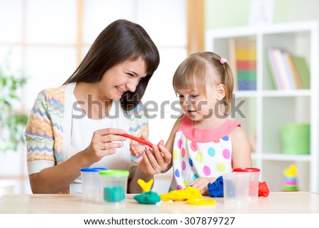 mother teaches her child to work with colorful play clay toys
