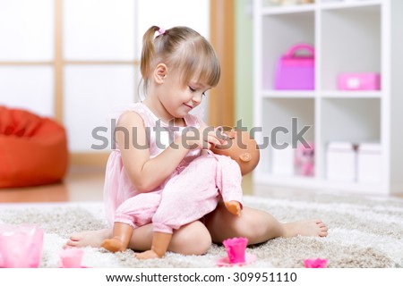 child girl playing with her baby-doll in day care center