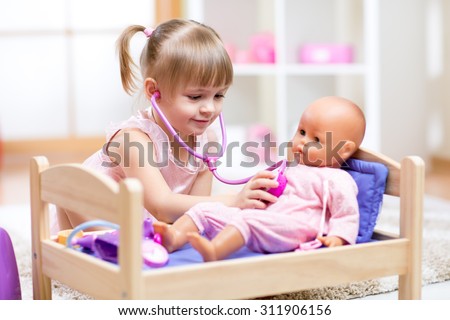 kid girl playing a doctor with doll in kindergarten
