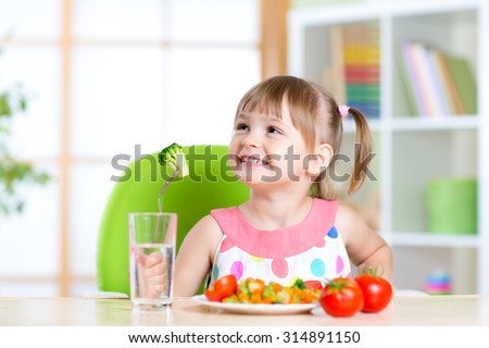 Kid eats healthy vegetables meal in home or nursery