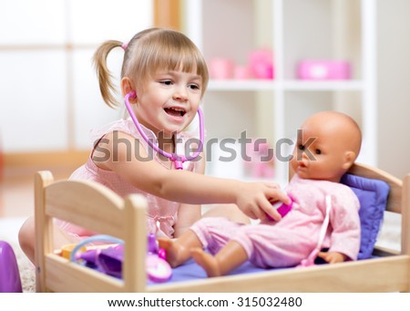 Child in kindergarten. Kid in nursery school. Little girl playing doctor with doll