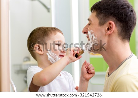 Playful father and his child son shaving and having fun in bathroom