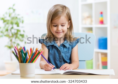 Portrait of child girl drawing with colorful pencils