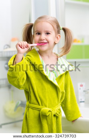 Smiling child kid little girl brushing teeth in bath