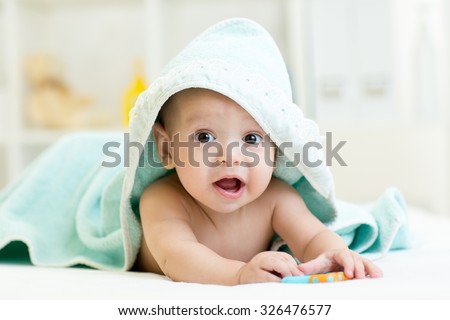 Adorable baby child under a hooded towel after bathing