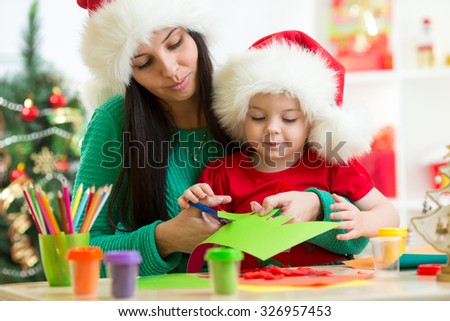 Mother and child cut christmas tree from paper preparing to holiday