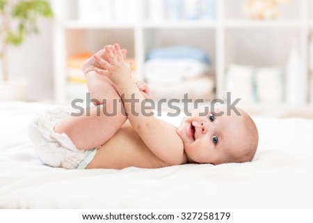 cute baby child little girl lying on her back and holding legs