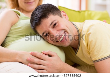 Happy future father listening to belly of  his pregnant wife