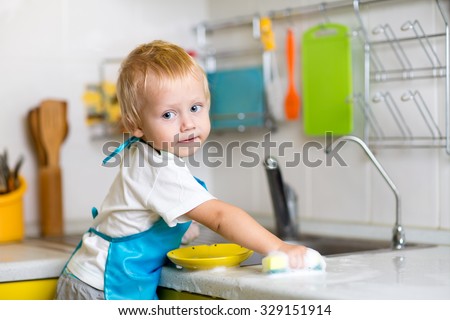 Child boy washing dishes in a domestic kitchen