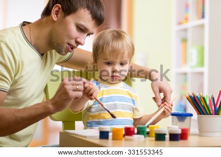 child boy with dad painting in nursery at home