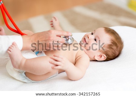 Pediatrician examines three months baby boy. Doctor using a stethoscope to listen to kid\'s chest checking heartbeat. Smiling child looking at doctor.