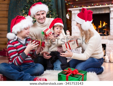 Family exchanging gifts in front of Christmas tree and fireplace