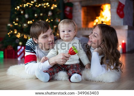 Happy family in living room in front of fire place near Christmas tree