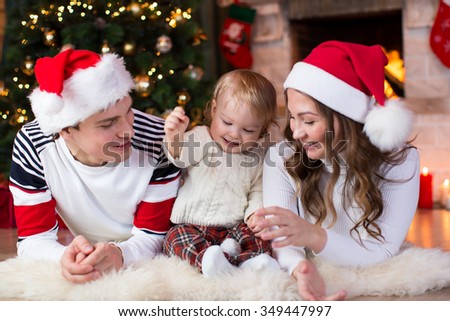 Happy family with child son lying near Christmas tree and fireplace  in living room