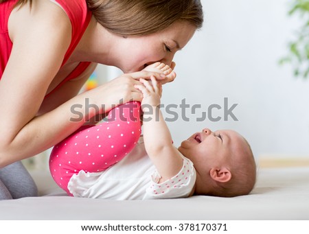 joyful mother playing with baby infant