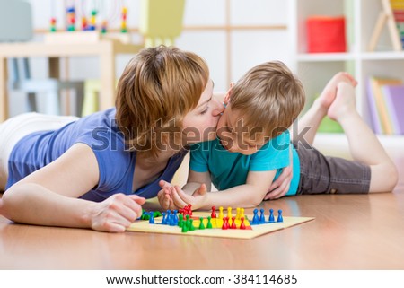 Family child and mom playing board game at home on the floor at home