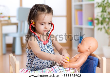 child girl playing doctor with doll at home